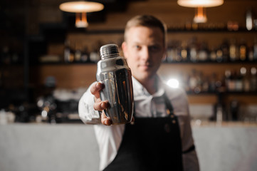 Bartender in white shirt and apron holding a shaker