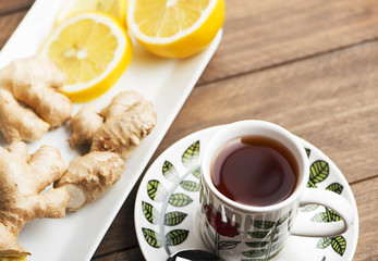 Tea cup with lemon and ginger on white plate. Infusion.