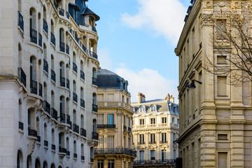 Typical residential buildings of Haussmannian and Art Deco style in chic neighborhoods of Paris, France, at sunset.