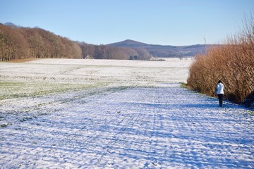 Obraz premium Person walking away down a snowy winter path