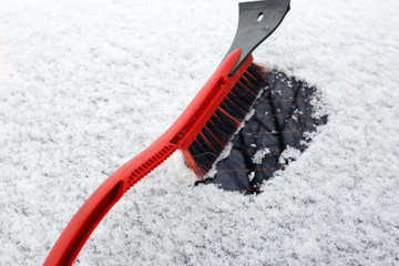 Man cleaning snow from car with brush