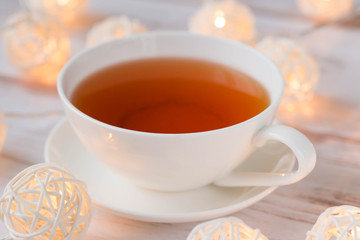 Cup of black tea and Christmas garlands glow