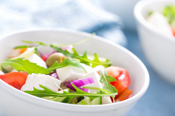 Fresh vegetable salad with feta cheese and olives in white bowl. Greek cuisine