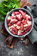 Fresh raw chicken hearts on dark background