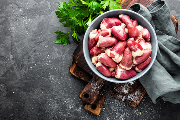 Fresh raw chicken hearts on dark background