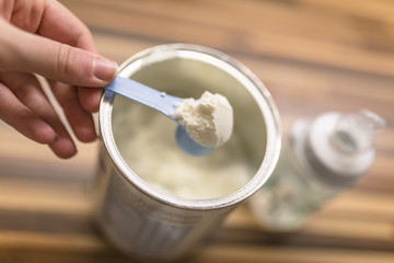 Powder milk for baby and blue spoon on light background close-up. Baby Milk Formula and Baby Bottles