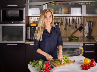 Young pretty young woman cooking salad in kitchen