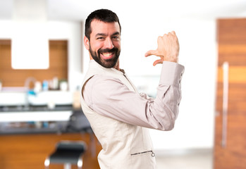 Handsome man with vest proud of himself inside house