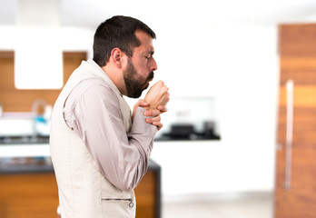 Handsome man with vest coughing a lot inside house