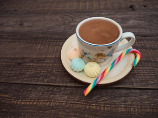 Cocoa with foam, sweet candy and colored bisse on a wooden table