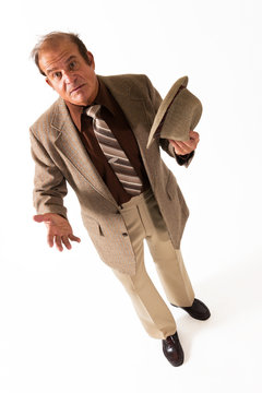 Older Man in Fine Suit Hat in Hand on White Background. An older gentleman in a fine suit and hat in hands in front of a plain, white background.