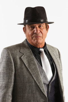 Older Man in Fine Gray Suit and Black Hat on White Background. An older gentleman in a fine gray suit in front of a plain, white background.