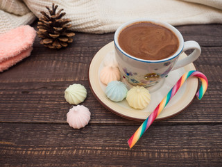 Cocoa with foam, sweet candy and colored bisse on a wooden table