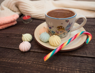 Cocoa with foam, sweet candy and colored bisse on a wooden table