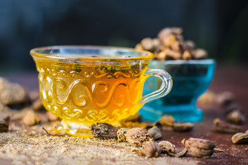 Close up of tea of Black cardamom with its powder and raw whole black cardamom.