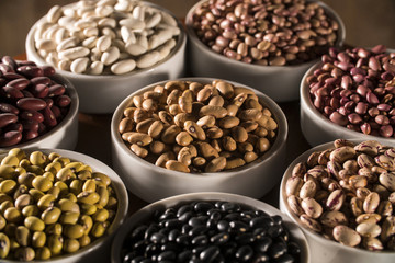 Assorted beans in bowls on wood background