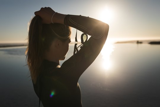 Woman tying her hair while standing near sea