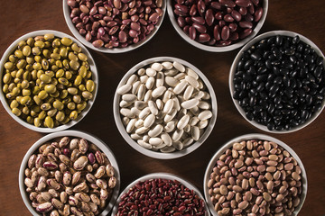 Assorted beans in bowls on wood background