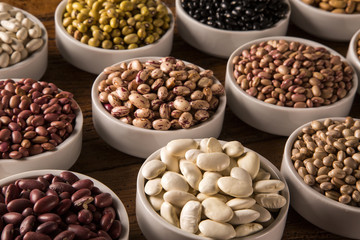 Assorted beans in bowls on wood background