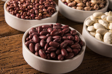 Assorted beans in bowls on wood background