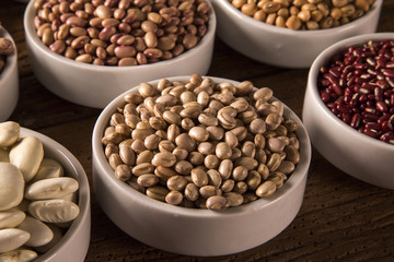 Assorted beans in bowls on wood background