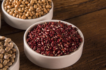 Assorted beans in bowls on wood background
