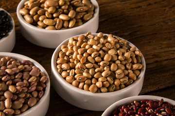 Assorted beans in bowls on wood background