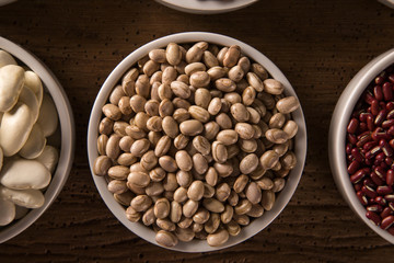 Assorted beans in bowls on wood background