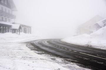 Snowy and icy road curve in a foggy weather - Vosges mountains (France) - horizontal