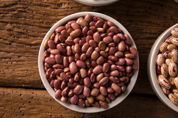 Assorted beans in bowls on wood background