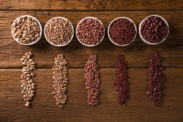 Assorted beans in bowls on wood background