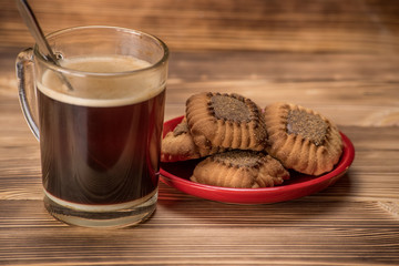 shortbread cookie and coffee in a transparent cup on a wooden background 