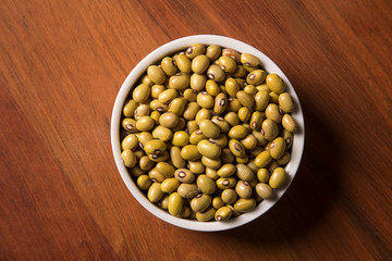 beans into a bowl on wooden background