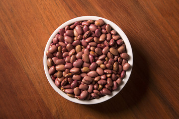 beans into a bowl on wooden background