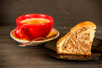 piece of pie on a black plate and coffee in a red cup on a dark wooden background 