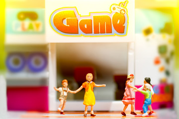 Miniature people, children enjoy with friend at game center