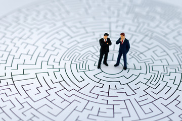 Miniature people: Businessman standing on center of maze. Concepts of finding a solution, problem solving and challenge..