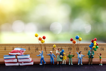 Miniature people, family and children standing hold colorful balloons  with ruler and books....