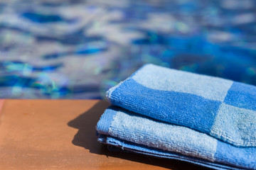 Fototapeta na wymiar Fluffy blue towel on border of a swimming pool