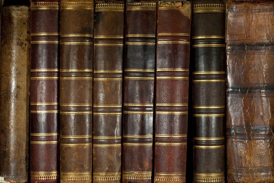background: a row of worn leather antiquarian book spines with gold embossing