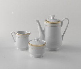 gold-rimmed white porcelain set for serving coffee and tea, on white background