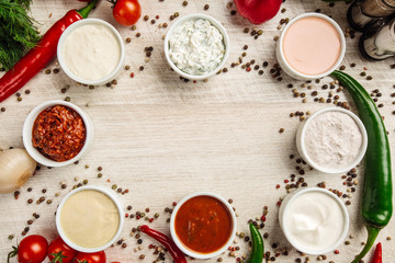 Set of sauces on white wooden background.