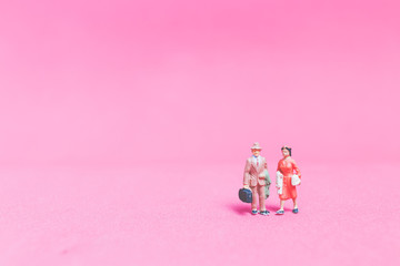 Fototapeta premium Miniature people : Couple of travellers on pink background&nbsp;, Valentine's day concept