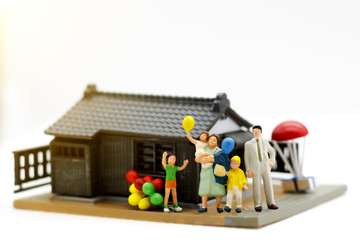 Miniature people, parents and children holding balloon with home ,family day concept.