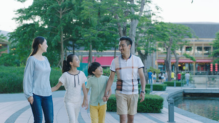 Asian family walking together on promenade, excited when looking at each other © allensima