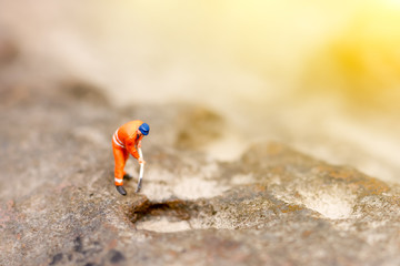 Miniature people: Male miner in uniform pickaxe the stones.