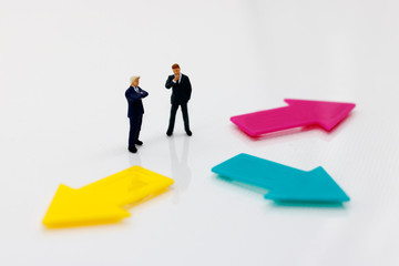 Miniature people standing with arrow pathway choice. Business decision concept.