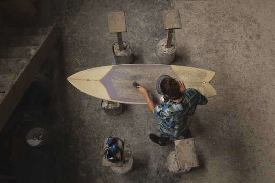 Overhead view of female worker making surfboard at workshop