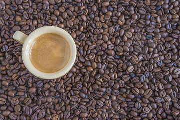 cup of espresso on coffee beans background top view