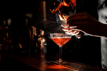 Les mains des barmans saupoudrent le jus dans le verre à cocktail